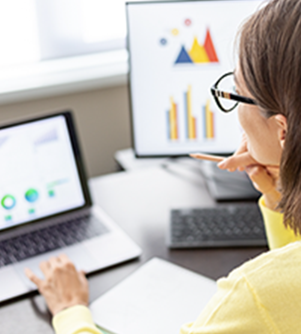 asset manager sitting at desk looking at marketing and sales data on her laptop